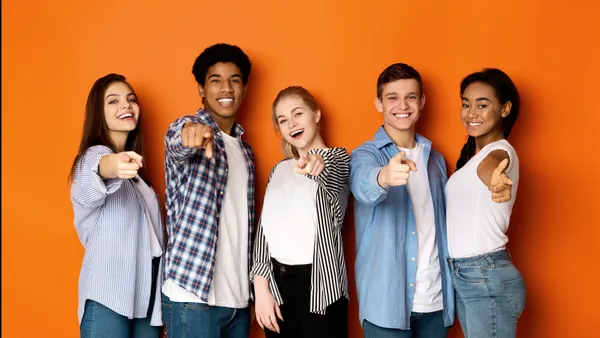 Group of smiling young adults pointing toward the camera