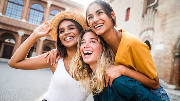 Three friends laughing together and showing bright, healthy smiles